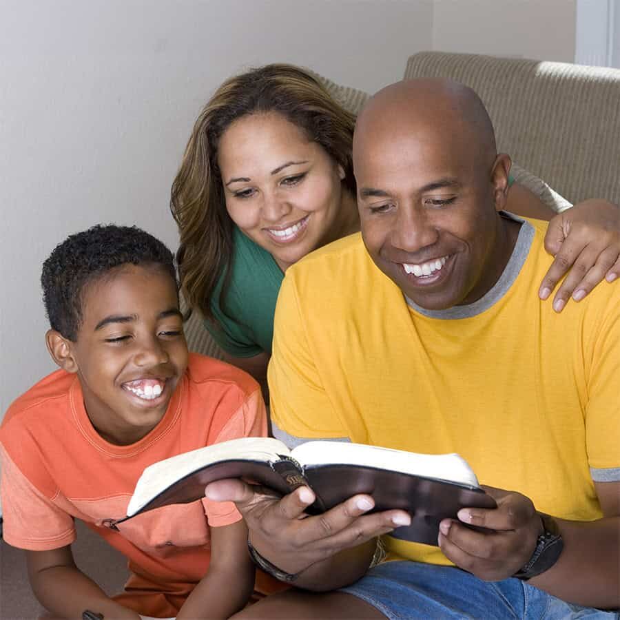 Happy African American family reading The Bible.